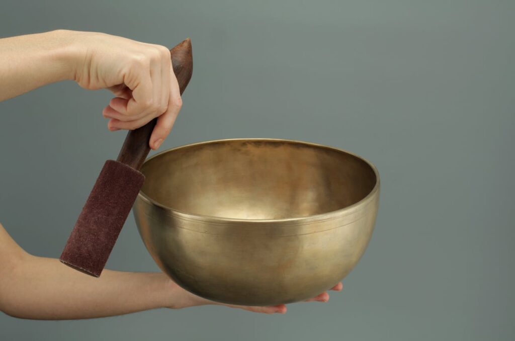 Close-up of a hand holding a Tibetan singing bowl used for meditation and relaxation.