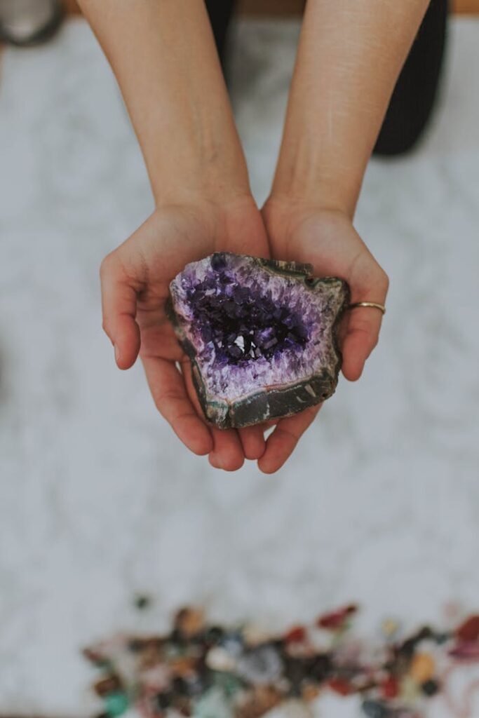 A close-up of hands holding a beautiful amethyst geode outdoors emphasizing its natural beauty.